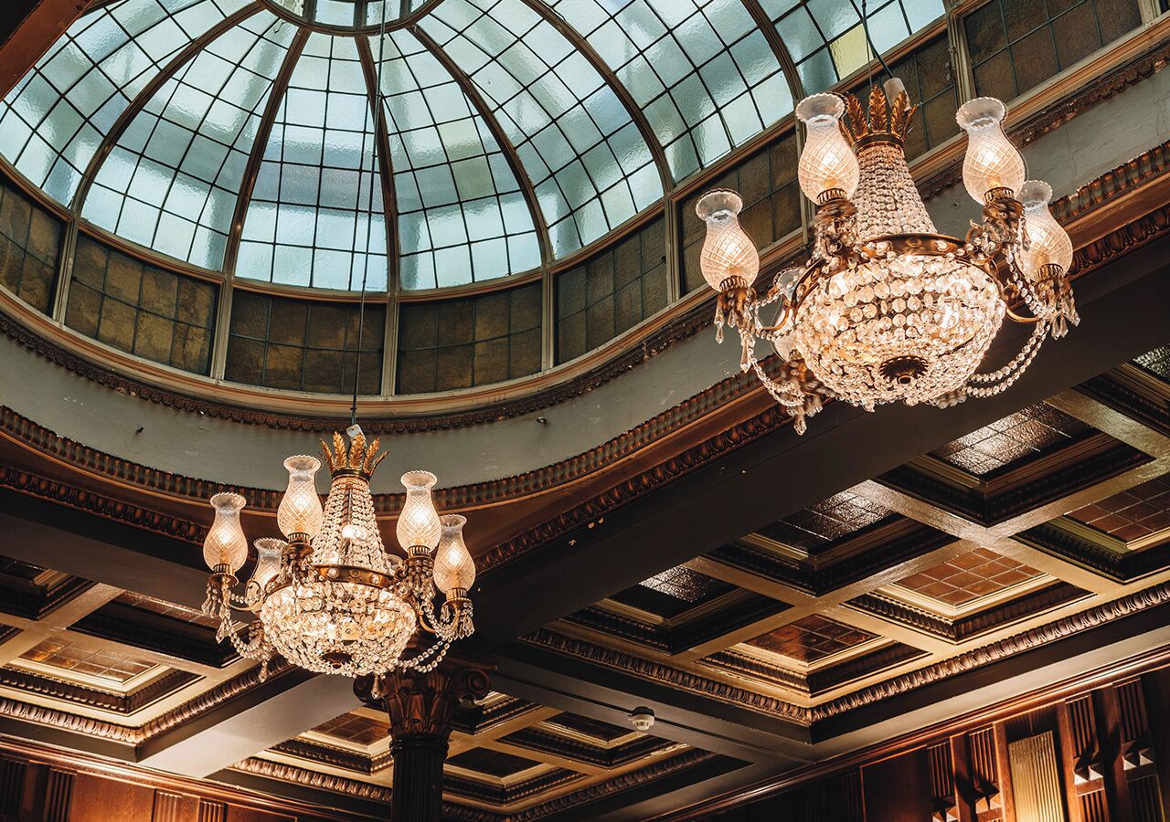 Un salón amplio con un gran techo abovedado de vidrio y candelabros ornamentales.