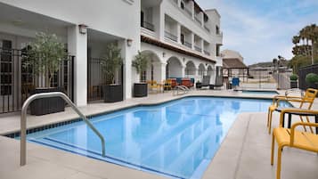 Una piscina al aire libre, sillones reclinables de piscina