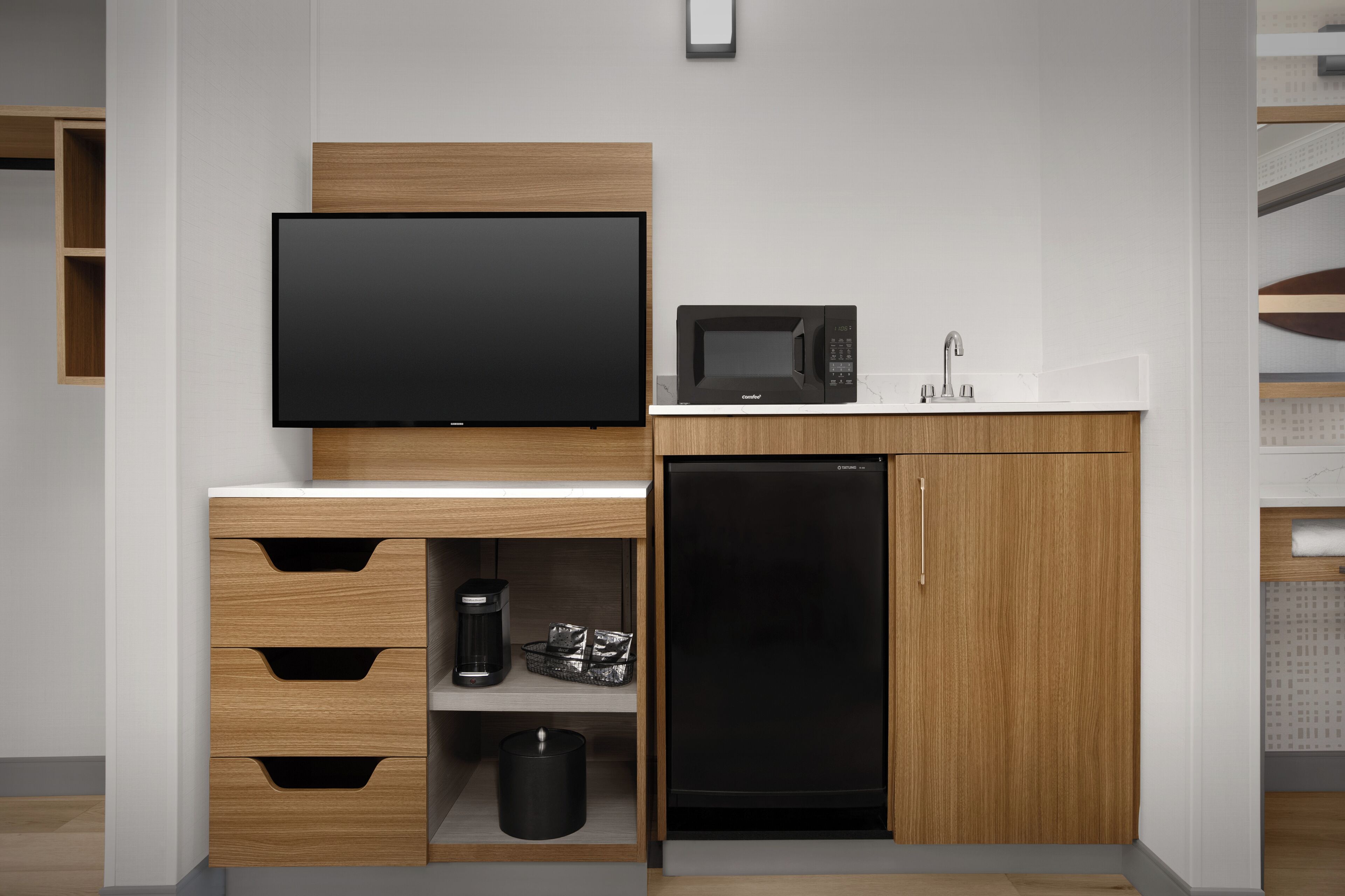 Una cocina moderna con televisión de pantalla plana, microondas, fregadero y lavavajillas.