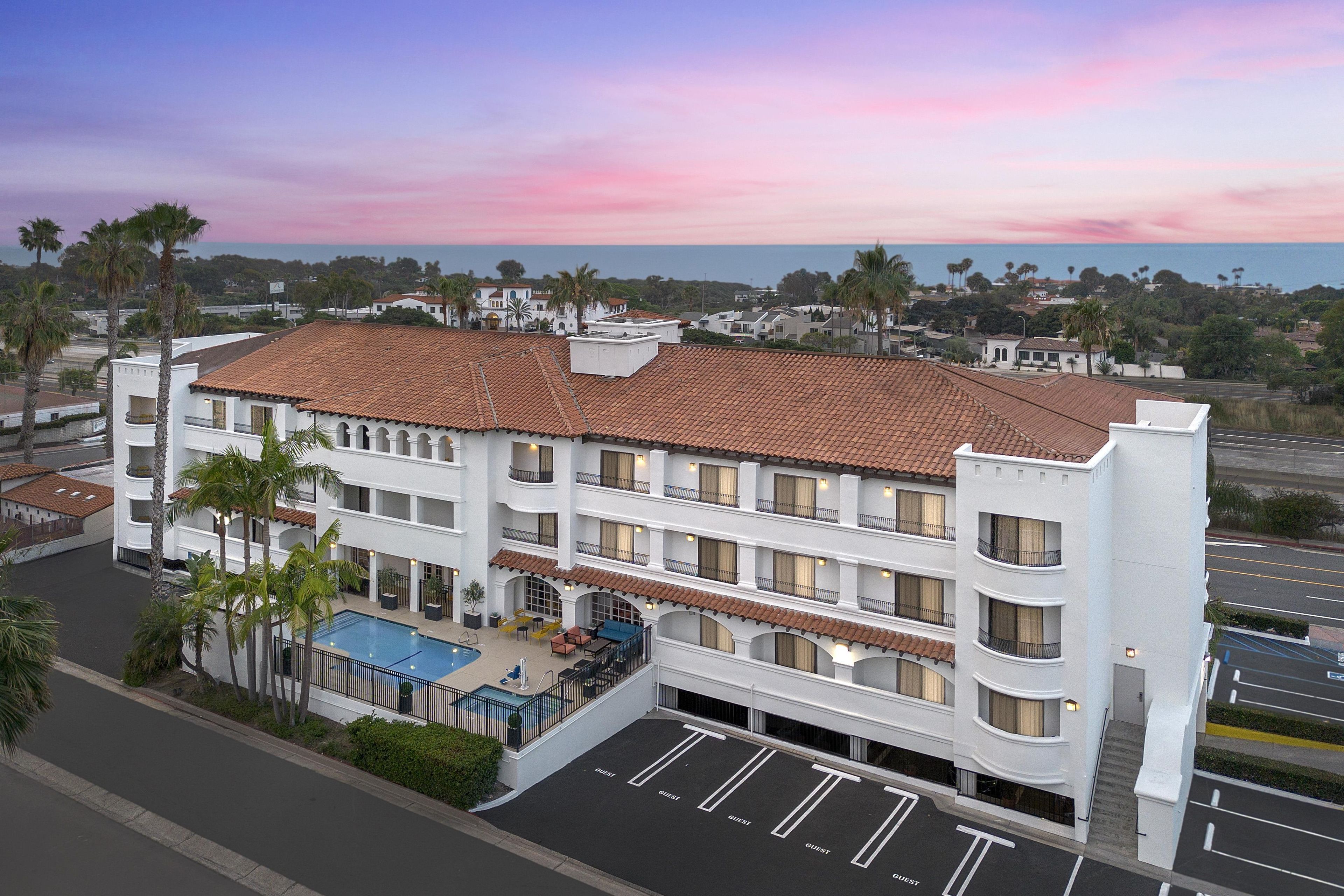A multi-story hotel with a rooftop pool and a view of the ocean.