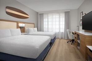 A hotel room with two beds, a desk, a chair, a TV, and a window with curtains.