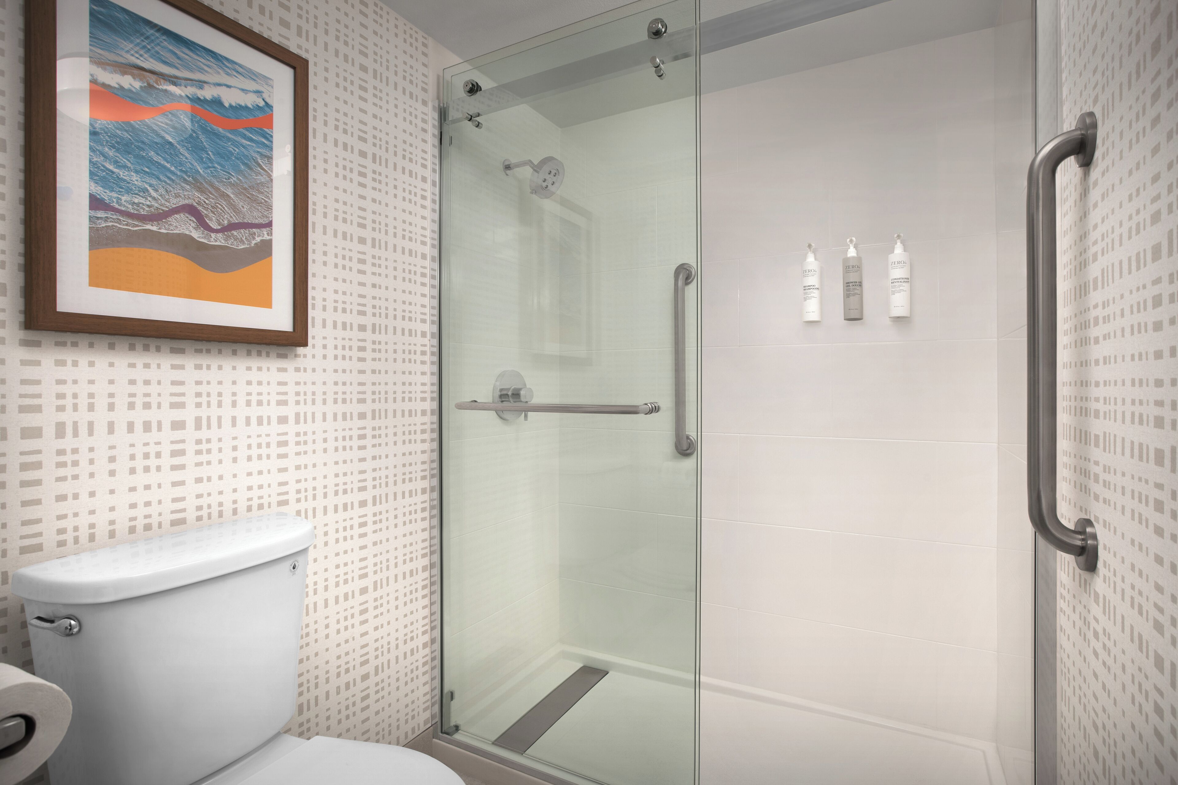Un baño moderno con cabina de ducha de vidrio, un inodoro y una obra de arte enmarcada en la pared.