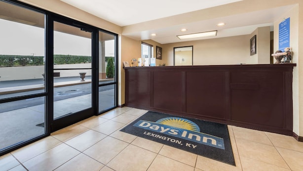 A hotel reception area with a reception desk, a large window, and a doormat with the hotel's logo.