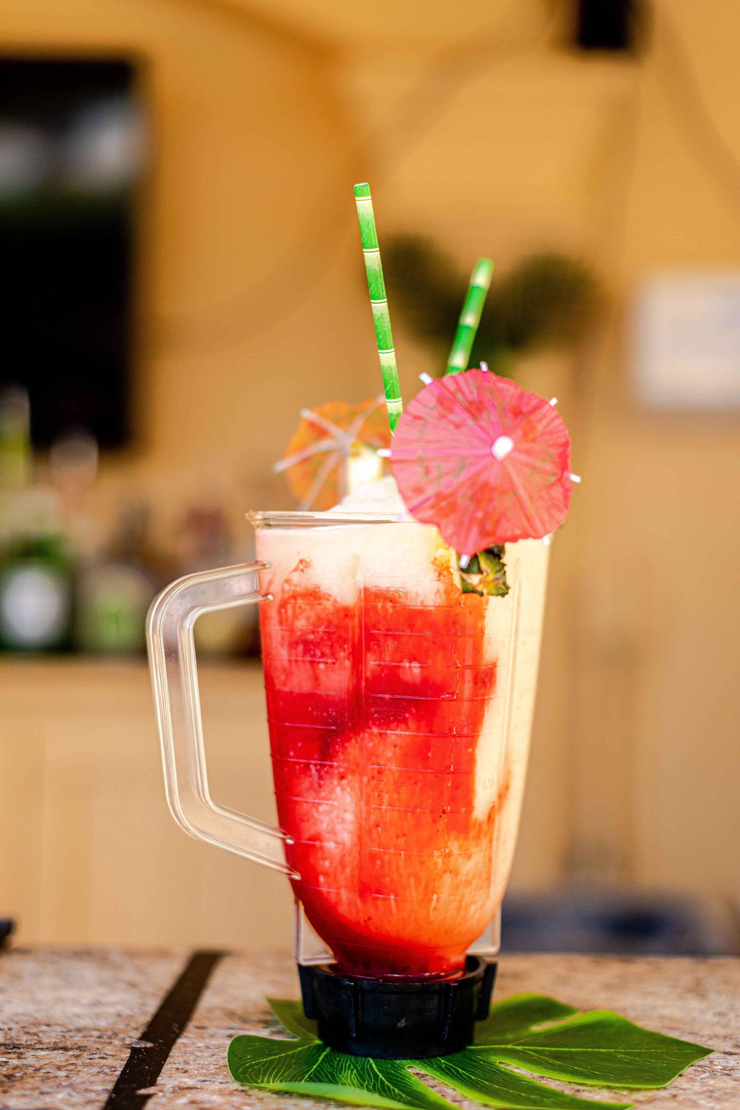 A cocktail in a glass with a straw and a decorative umbrella.