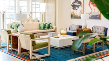 Un salon moderne avec un canapé, des fauteuils, une table basse et des œuvres d’art accrochées aux murs.