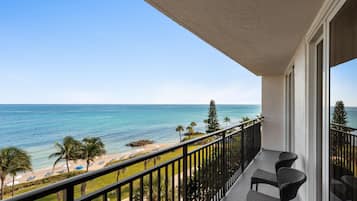Un balcon avec vue sur l’océan, une plage et des palmiers.