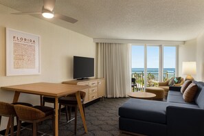 A hotel room with a flat-screen TV, a dining table, a sofa, and a balcony with a view of the ocean. - Embassy Suites by Hilton Deerfield Beach Resort & Spa (Deerfield Beach)