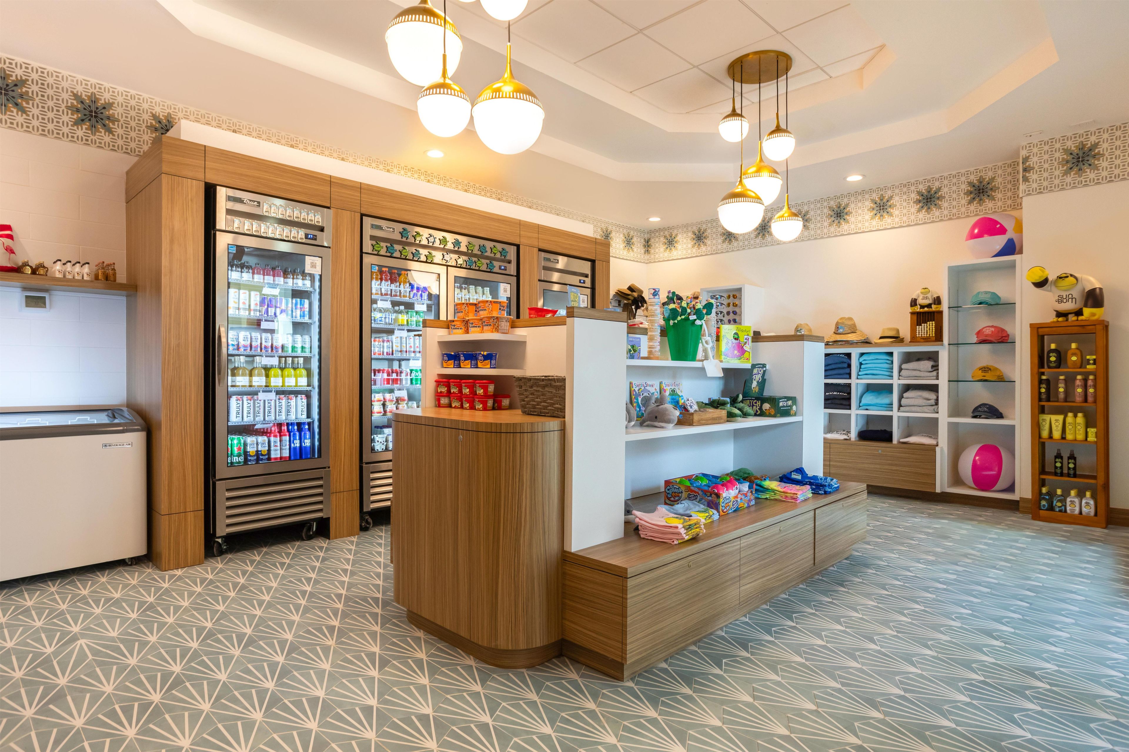 A brightly lit retail space with wooden shelving, a beverage cooler, and various products including toys and personal care items.