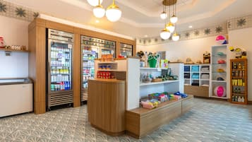 A brightly lit retail space with wooden shelving, a beverage cooler, and various products including toys and personal care items.