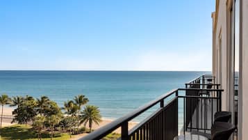 A balcony with a view of the ocean and palm trees.