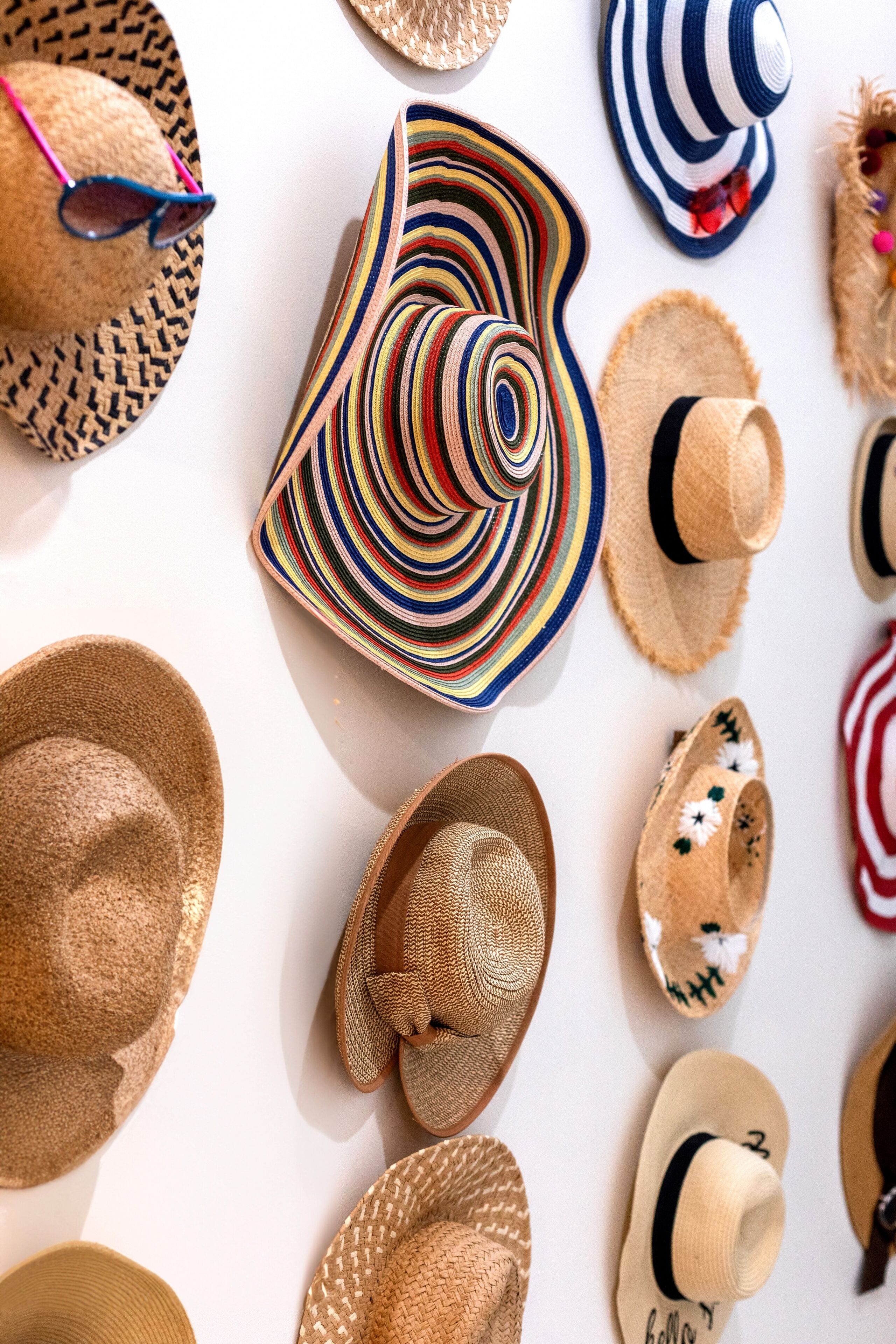 Une variété de chapeaux et de lunettes de soleil disposés sur une surface blanche.