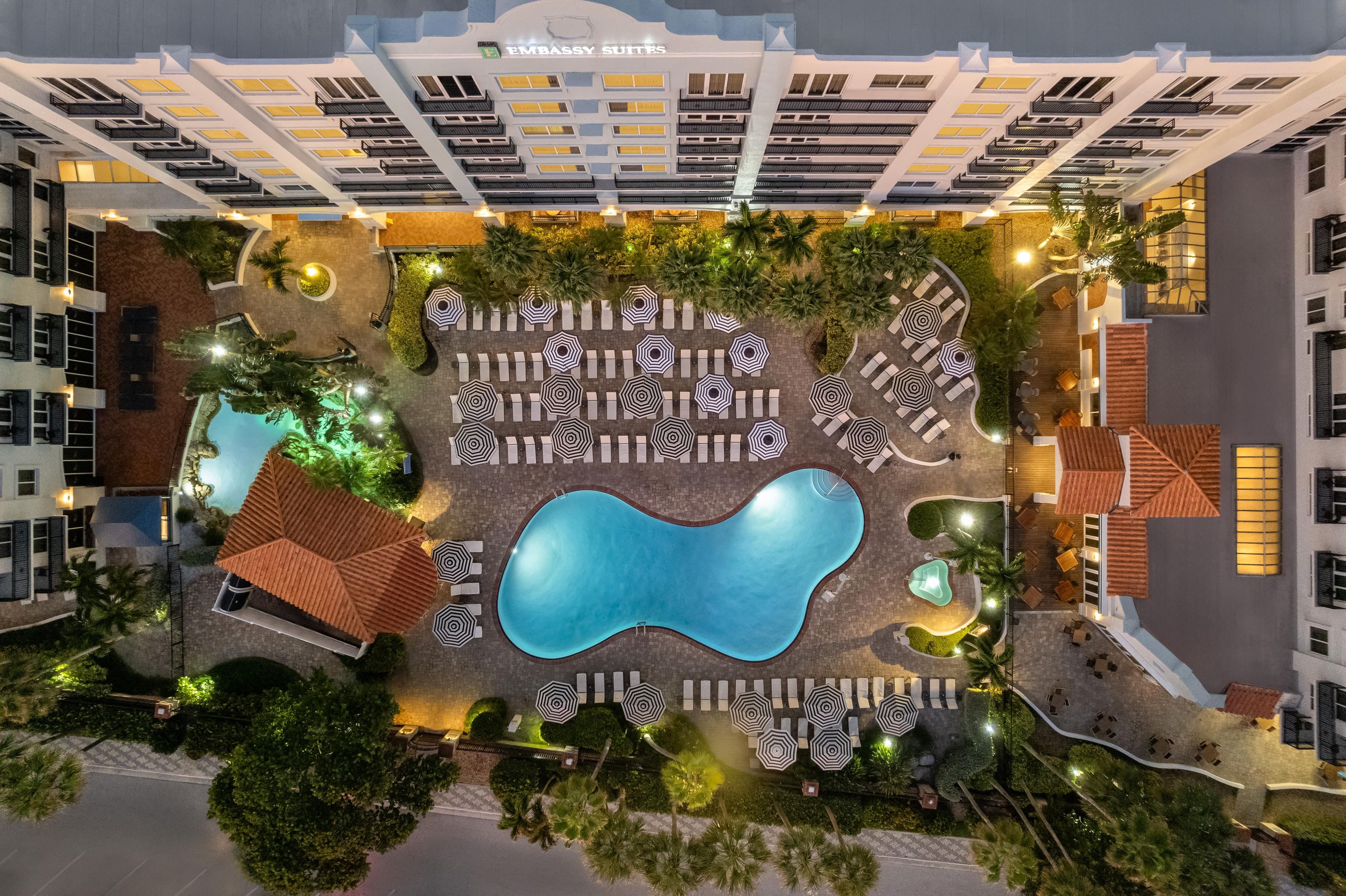 A hotel with multiple floors, a swimming pool, and outdoor seating areas.