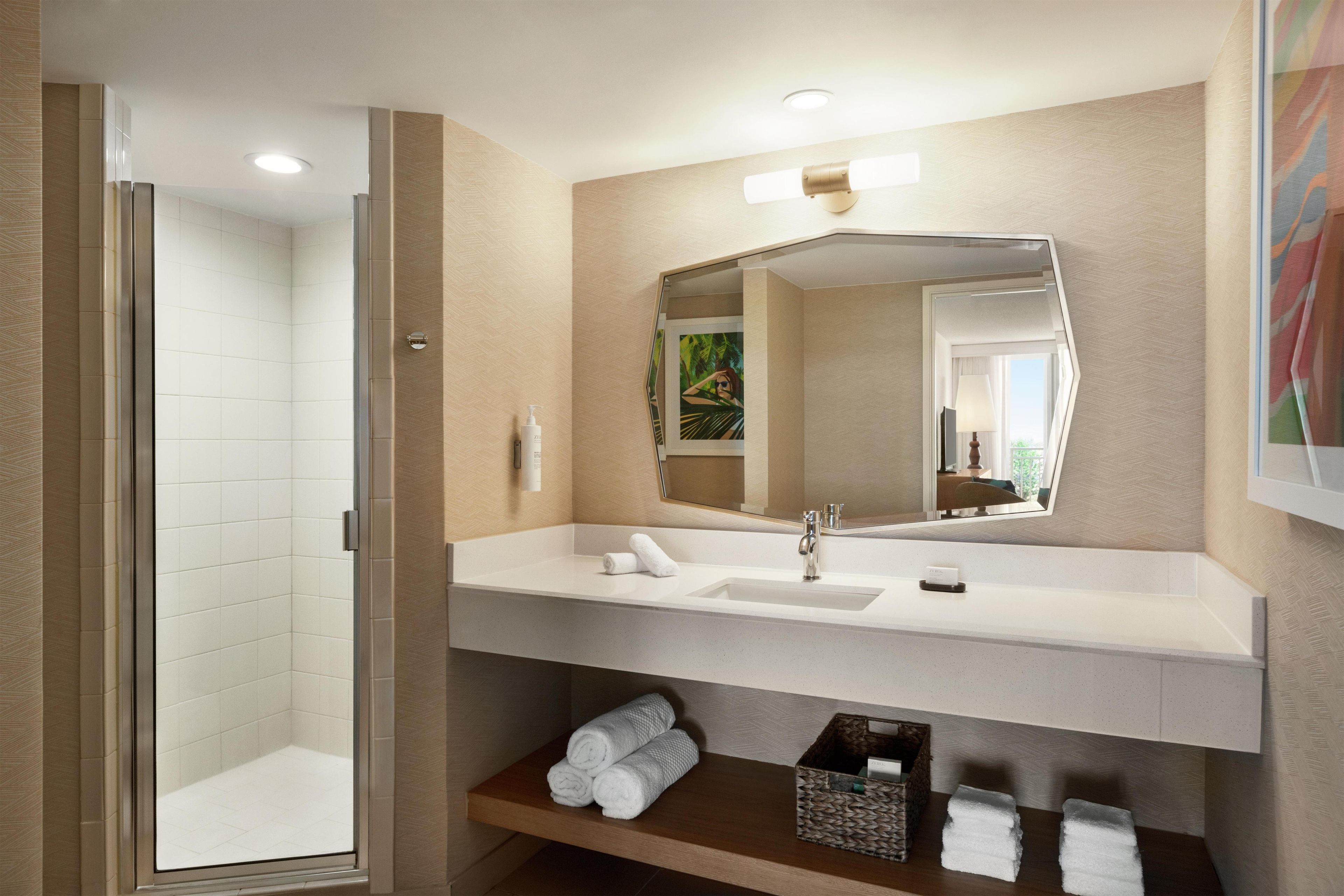 A modern bathroom with a shower, a sink, and a mirror.