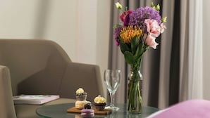 Une table en verre avec des pâtisseries, un vase de fleurs et un magazine sur un canapé.