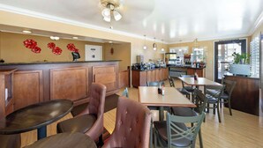 A restaurant with wooden furniture, a ceiling fan, and a kitchen area. - Best Western Hanford Inn (Hanford)