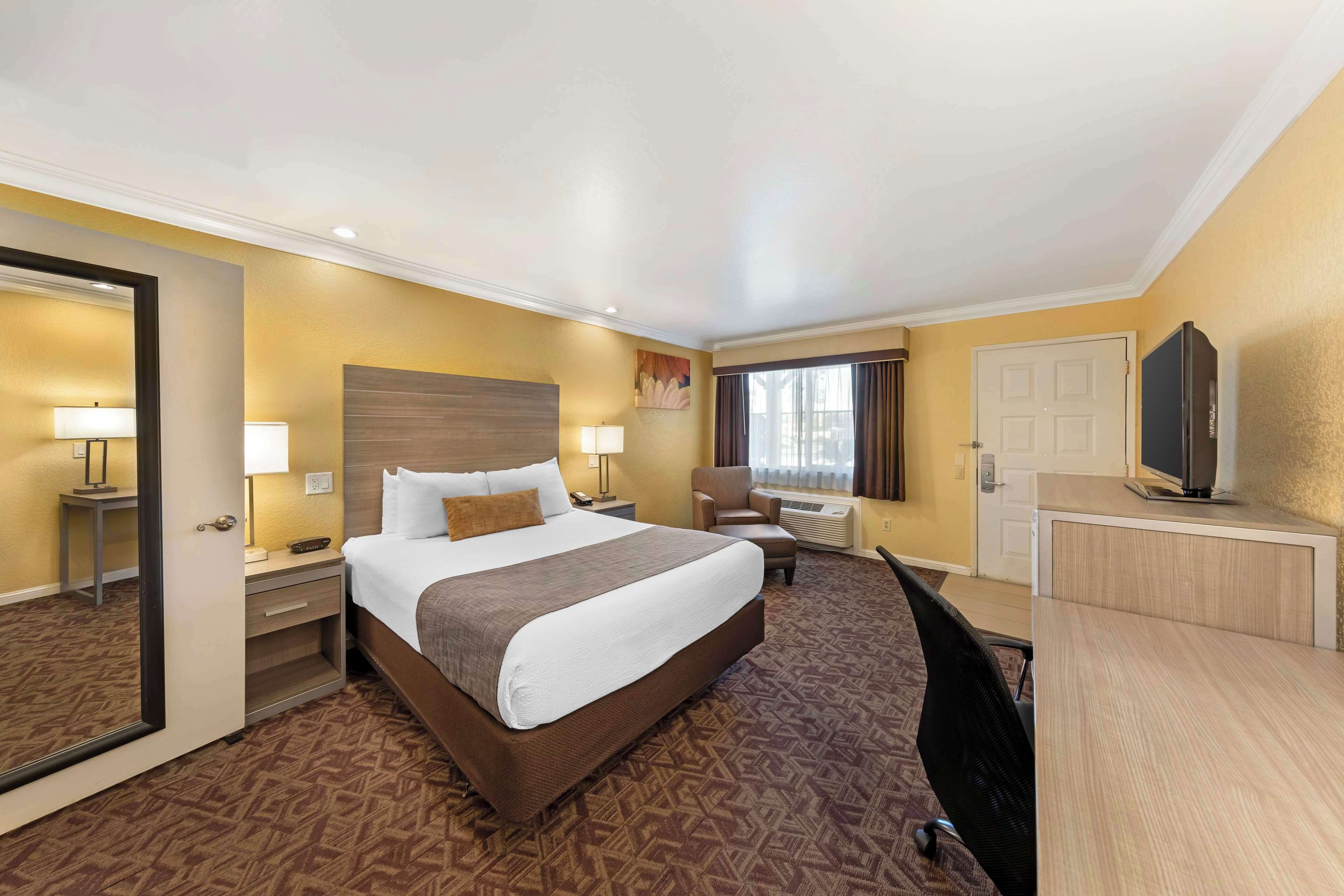 Une chambre d’hôtel avec un grand lit, un bureau, une chaise, une télévision et une porte.