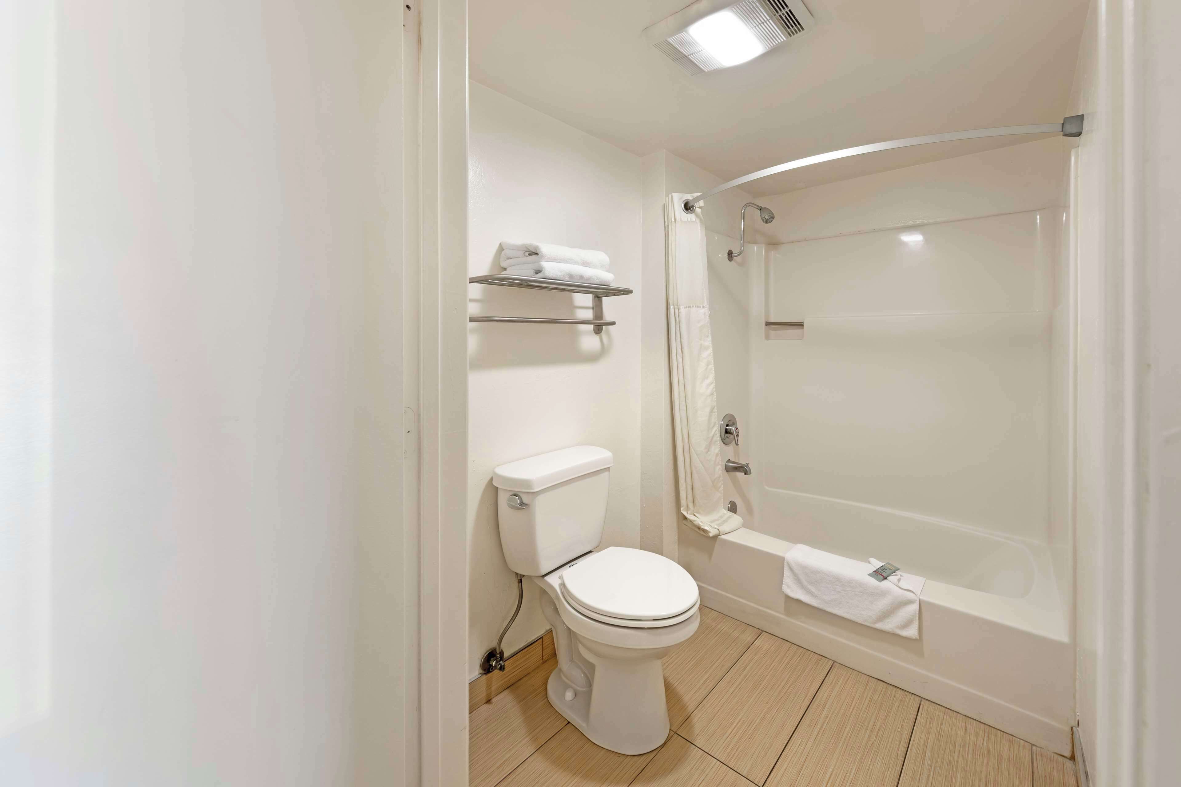A bathroom with a toilet, a shower, and a towel rack.