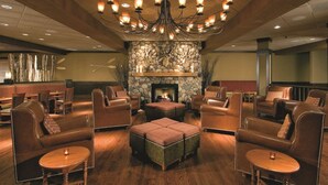 A spacious lobby with leather seating, a stone fireplace, and a chandelier. - DoubleTree by Hilton Chicago - Arlington Heights (Arlington Heights)