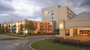A DoubleTree by Hilton hotel with a modern design, featuring large windows and a well-lit entrance. - DoubleTree by Hilton Chicago - Arlington Heights (Arlington Heights)