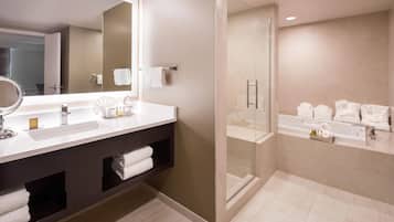 A modern bathroom with a large mirror, a vanity with a sink, a shower area, and a bathtub.