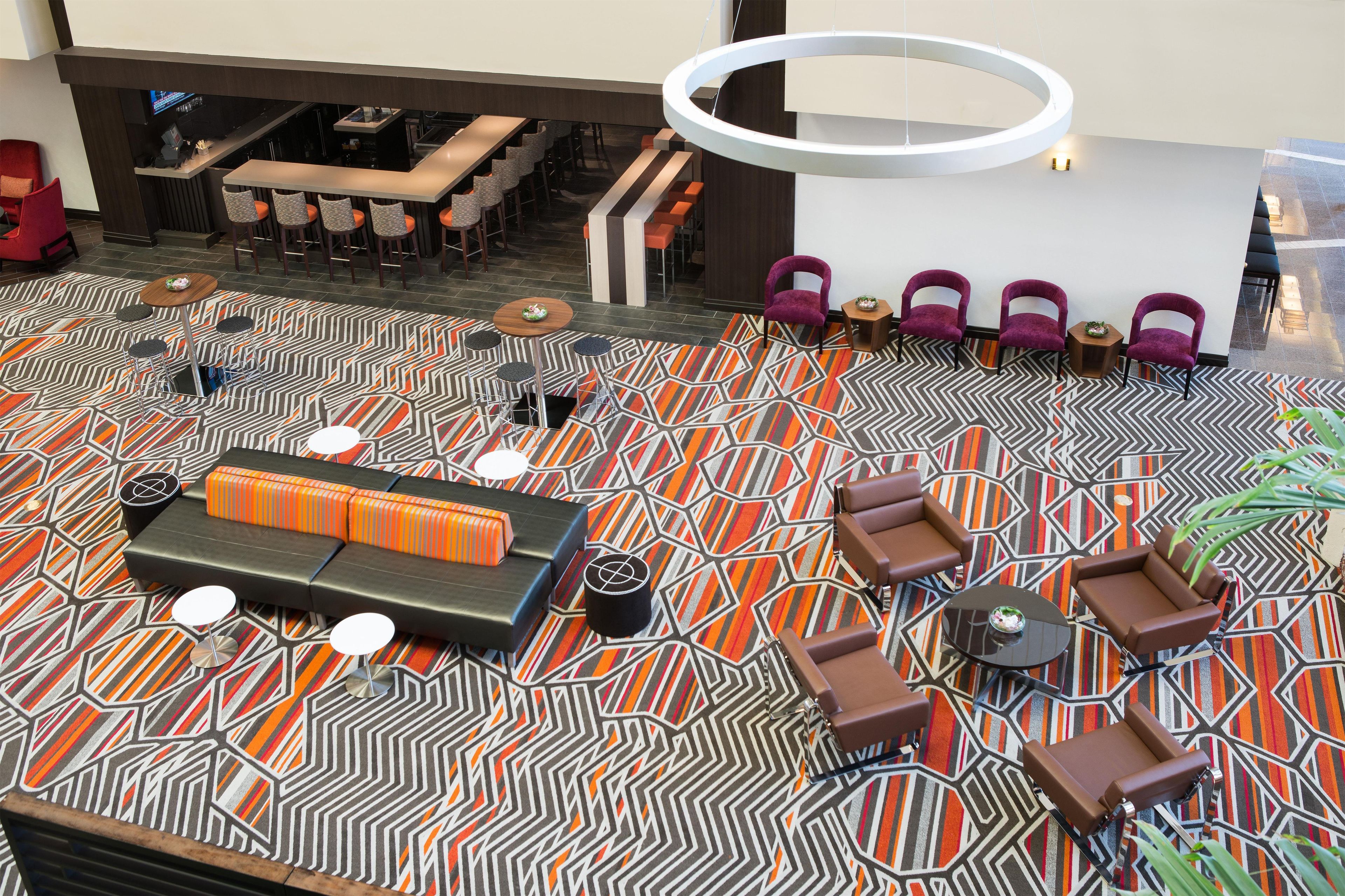 A spacious lobby with a patterned carpet, seating areas, and a bar.