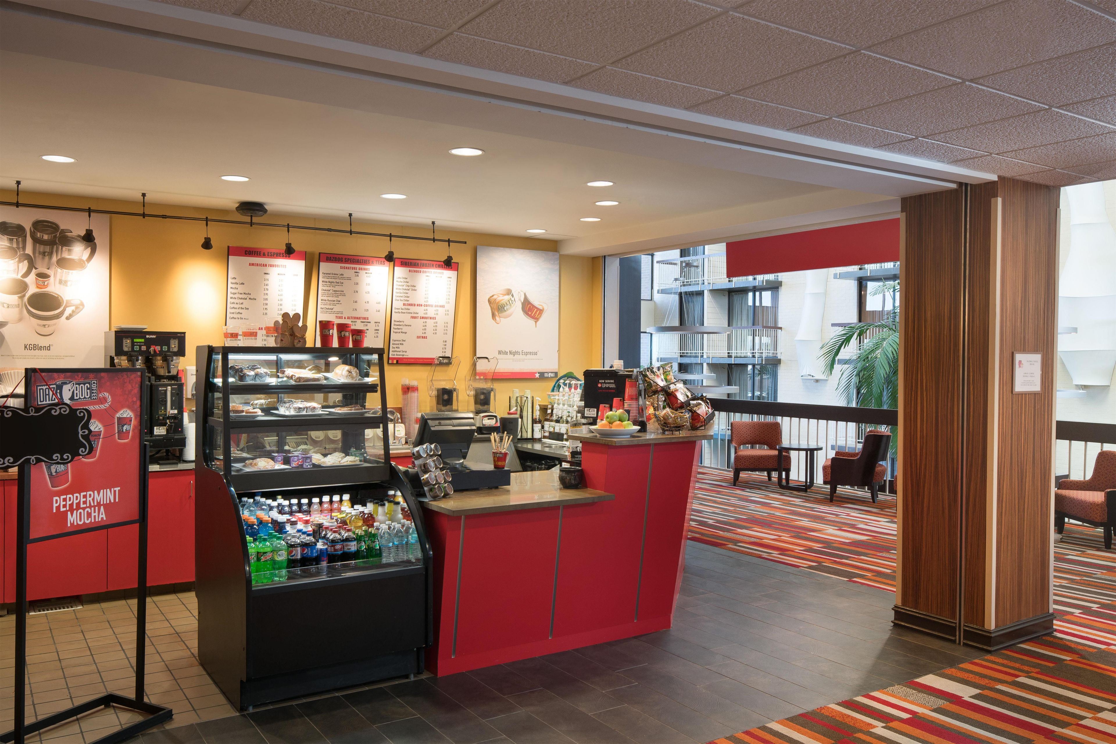 A coffee shop with a red counter, menu boards, and a beverage dispenser.