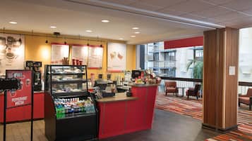 A coffee shop with a red counter, menu boards, and a beverage dispenser.