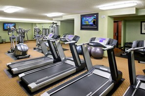 A gym with Nautilus treadmills, elliptical machines, and a TV screen displaying a workout video. - DoubleTree by Hilton Denver Tech Center (Greenwood Village)