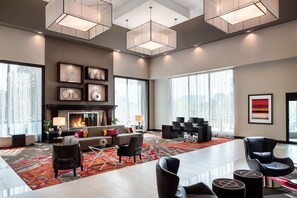 A spacious living area with a fireplace, modern furniture, and large windows. - DoubleTree by Hilton Denver Tech Center (Greenwood Village)