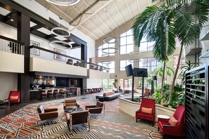 A spacious lobby with a high ceiling, multiple seating areas, and a bar. - DoubleTree by Hilton Denver Tech Center (Greenwood Village)