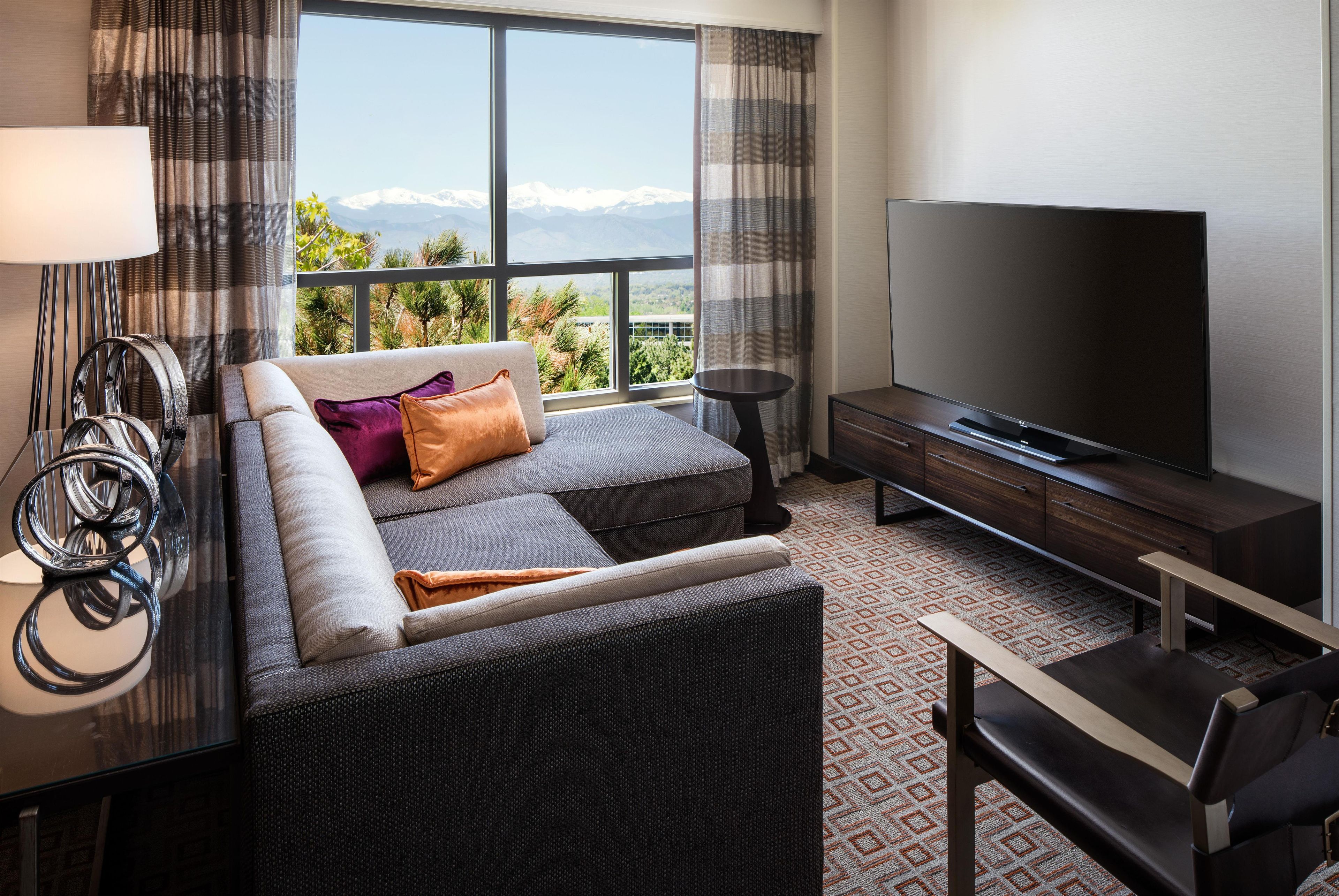 Une chambre d’hôtel moderne avec un canapé, une télévision et une vue sur les montagnes.