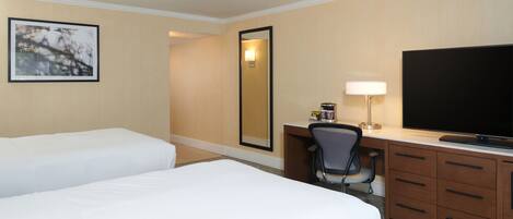 A hotel room with two beds, a desk with a chair, a television, and a mirror.