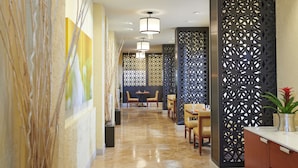 A hotel lobby with a long corridor, seating area, and decorative panels. - DoubleTree by Hilton Hotel Salt Lake City Airport (Salt Lake City)