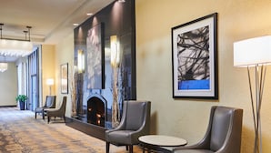 A hotel lobby with a fireplace, seating area, and artwork on the walls. - DoubleTree by Hilton Hotel Salt Lake City Airport (Salt Lake City)