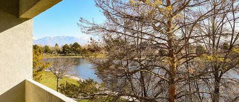 Vista desde un balcón con vista a un lago y montañas al fondo.