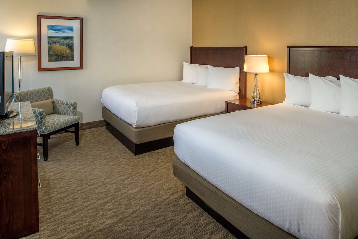 A hotel room with two beds, a desk, and a chair.