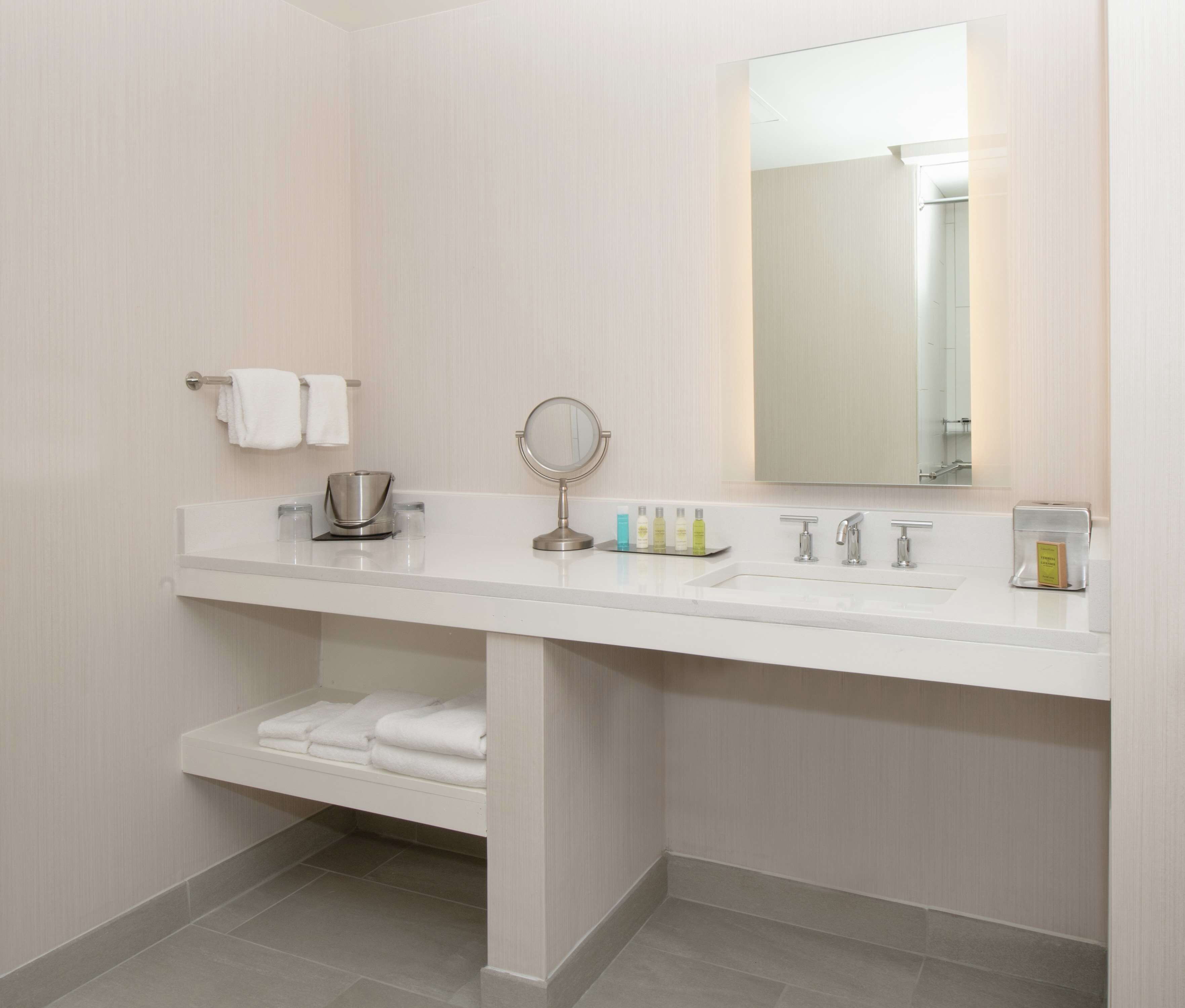 A modern bathroom with a white vanity, a round mirror, and a large mirror above the sink.
