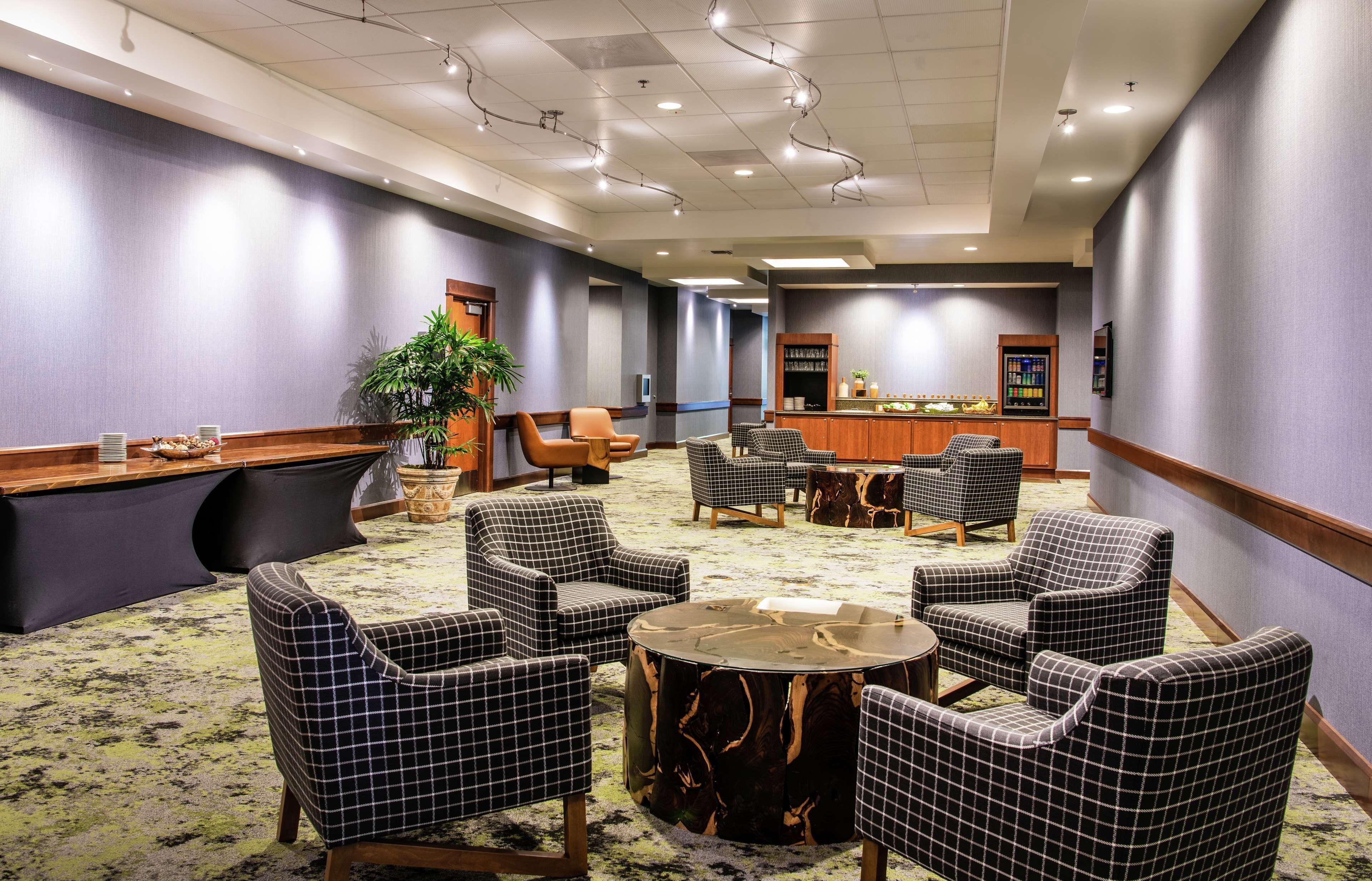 A hotel lobby with checkered chairs, a reception desk, and a coffee bar.