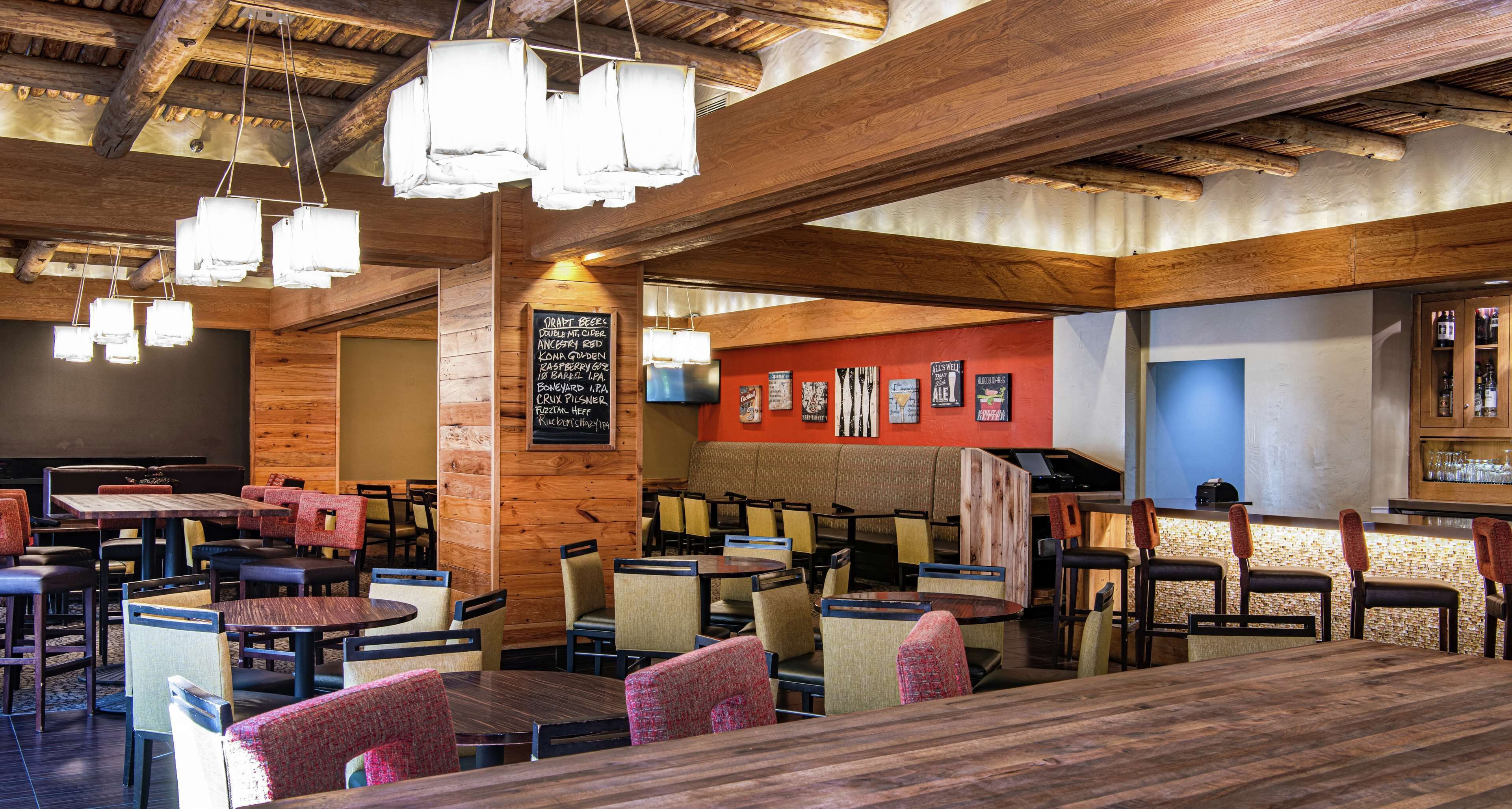 A restaurant with wooden ceiling beams, multiple tables and chairs, and a menu board on the wall.