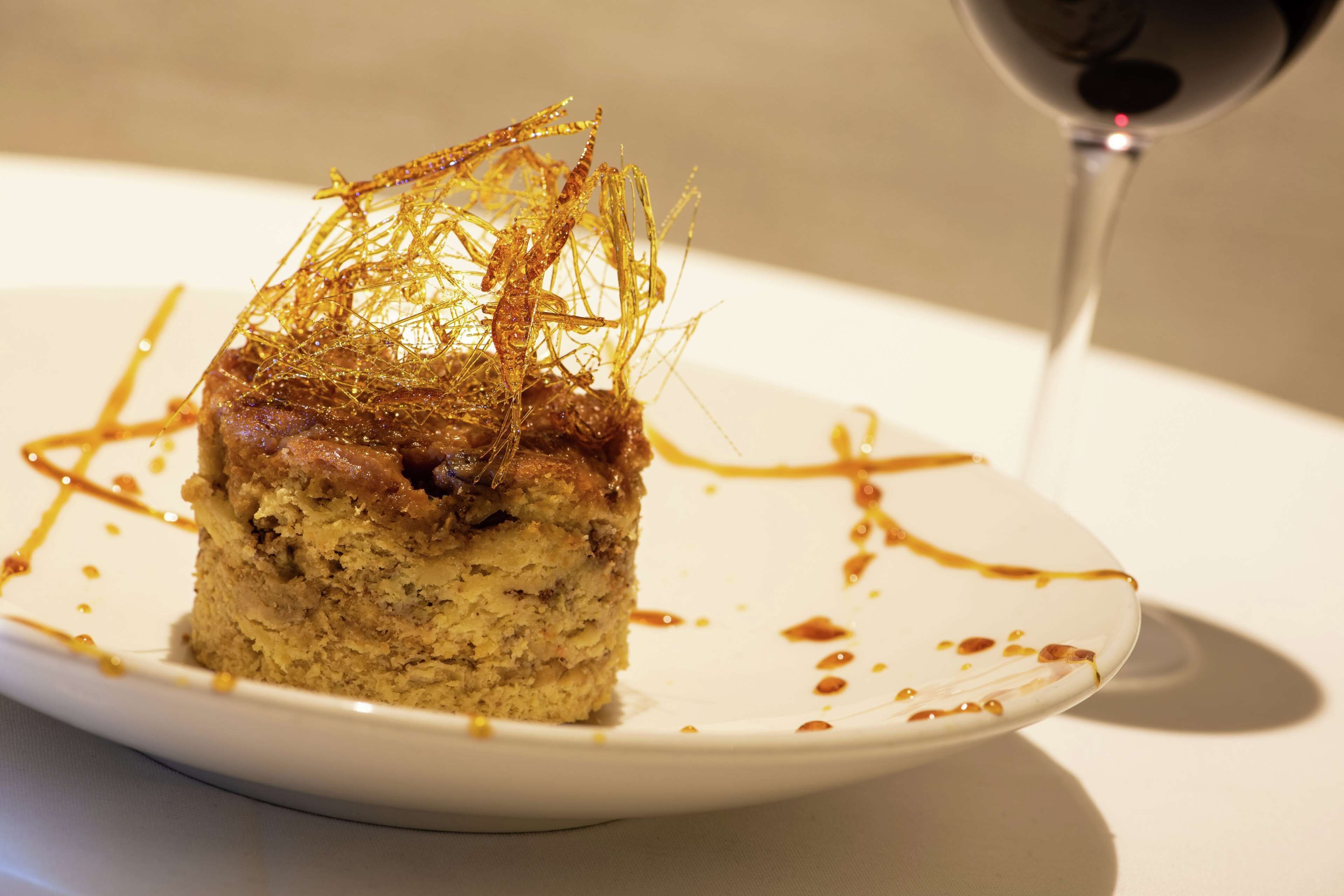 A dessert on a plate with a glass of red wine.