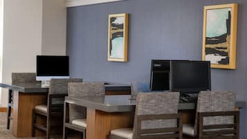 Una camera d'albergo con una scrivania, due monitor e quattro poltrone imbottite.