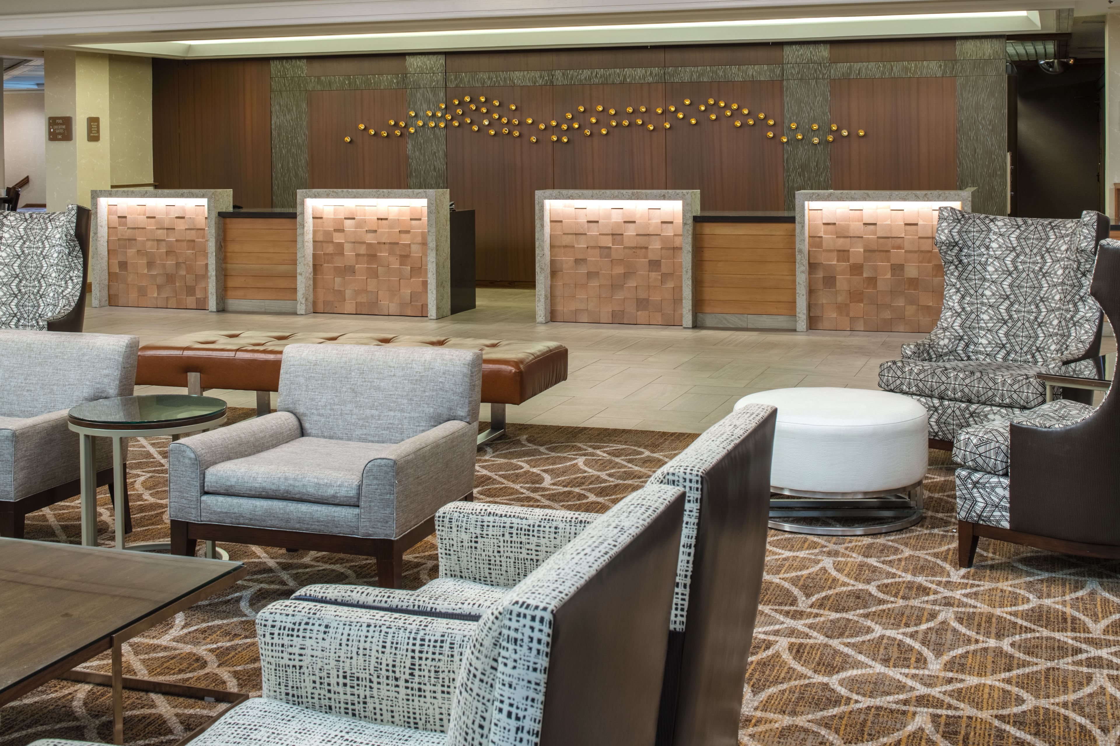 A lobby with seating areas, a reception desk, and a patterned carpet.