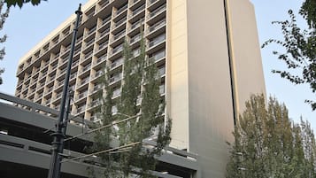 Un edificio moderno con un letrero grande, un estacionamiento y un tren que pasa.