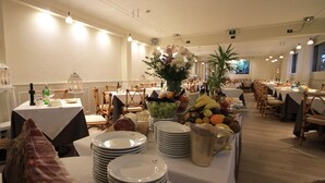 A dining area with tables set for a meal, featuring a variety of fruits and a centerpiece. - Raffaelli Park Hotel (Forte dei Marmi)