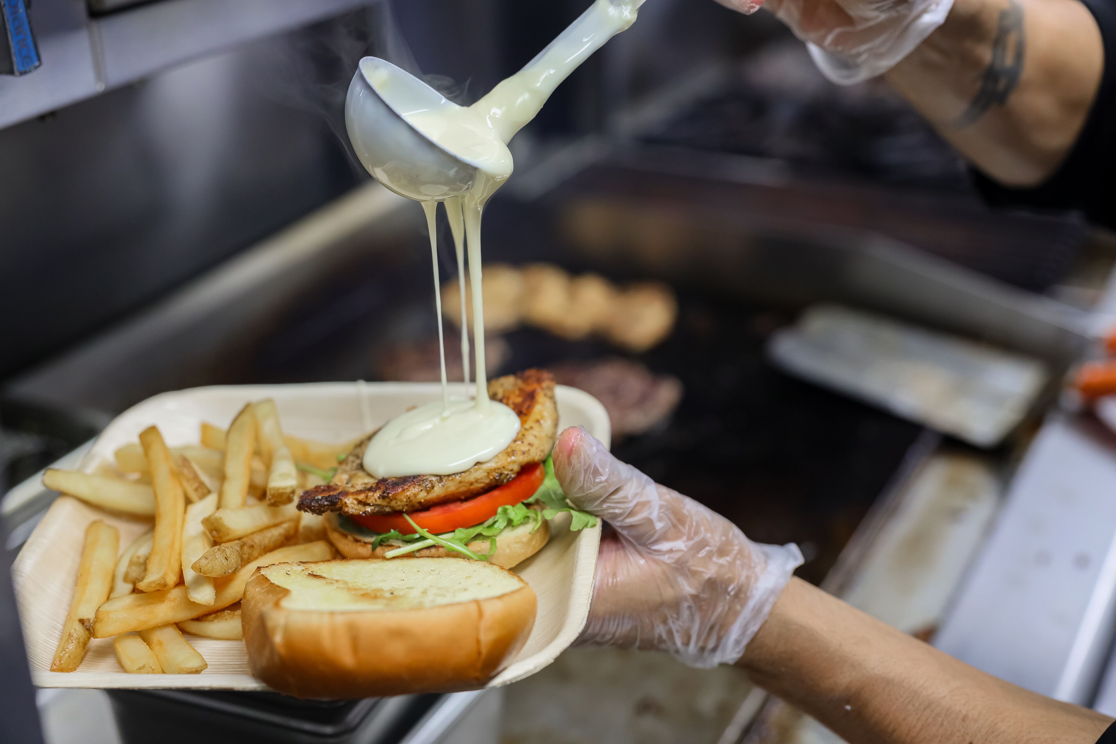 A person holding a tray with a burger, fries, and a drink.