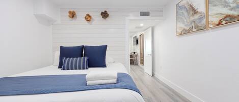 A modern bedroom with a bed, blue bedding, and a ceiling fan.