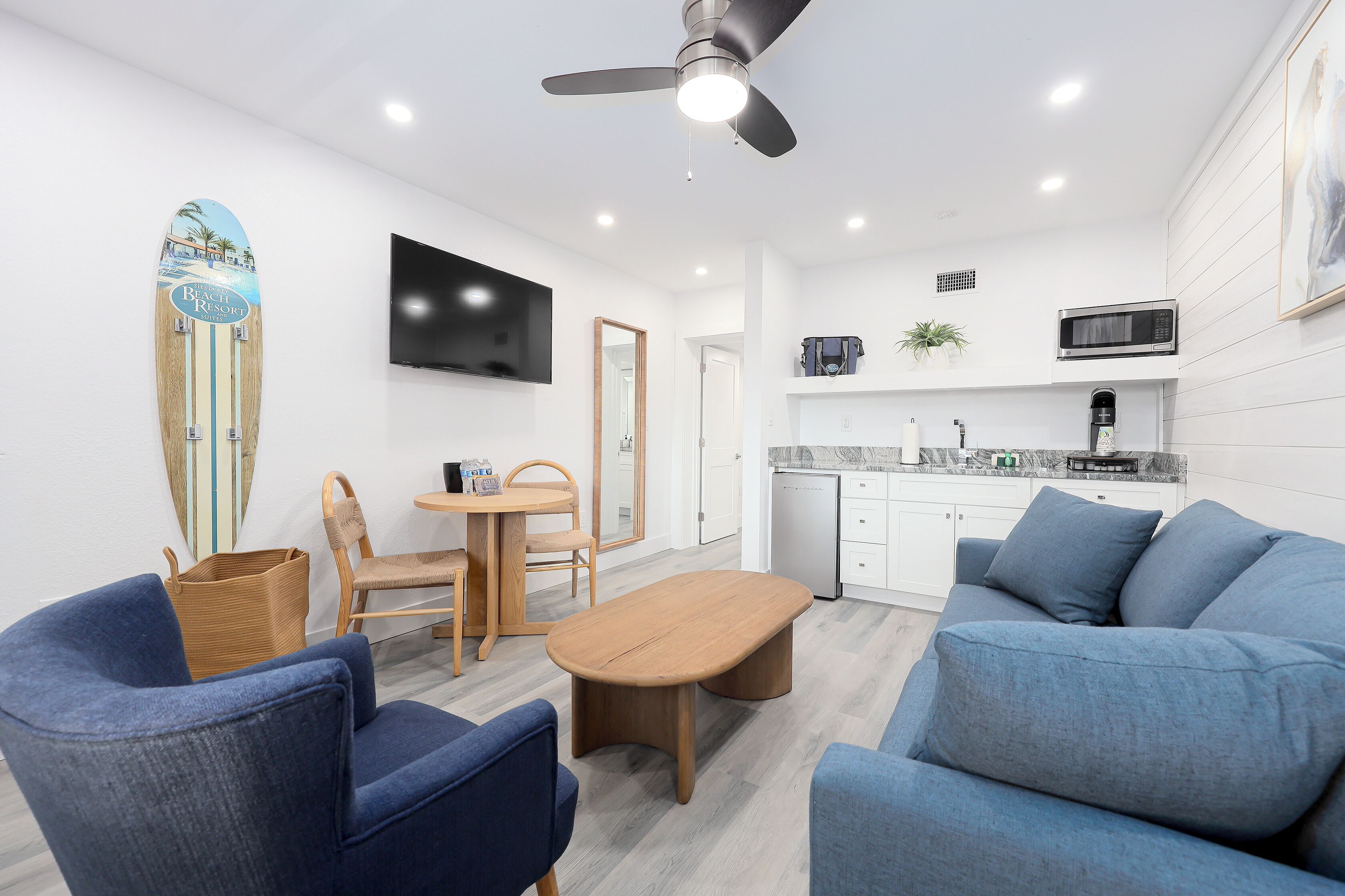 Un salon moderne avec un canapé bleu, une table basse en bois et un coin repas comprenant une table et des chaises en bois.