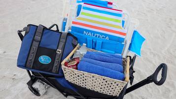 Ein Liegestuhl mit einem bunten Streifenhandtuch und einer blauen Tasche mit dem Aufdruck "NAUTICA" am Strand.