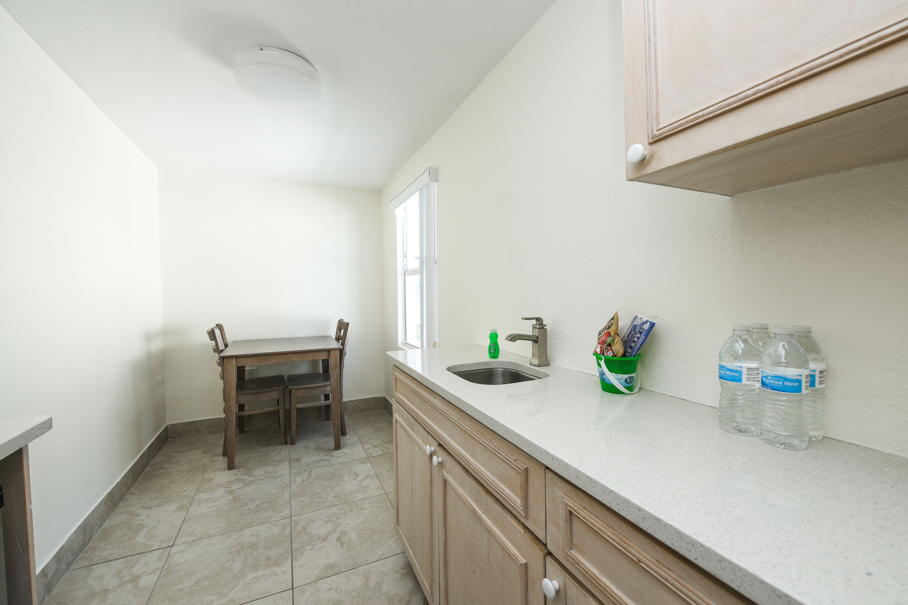 A small kitchen with a sink, a wooden table, and cabinets.