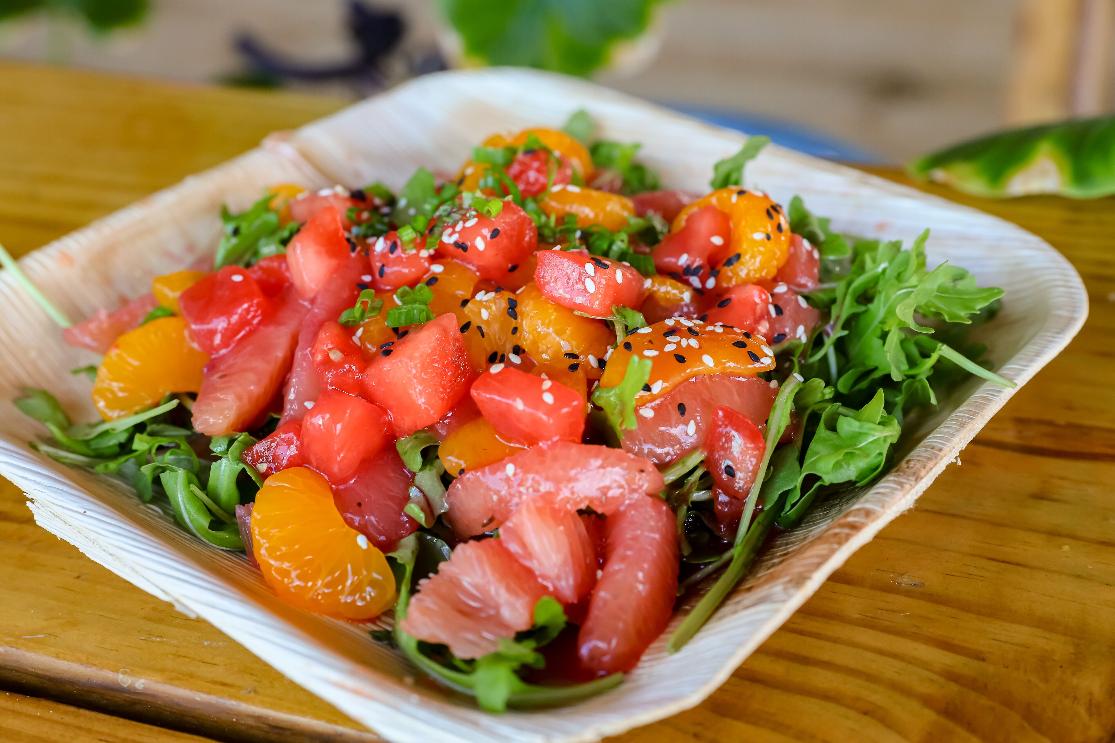 Ensalada con diversos vegetales y frutas sobre una mesa de madera.
